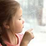 Pige foran regnvåd vindue